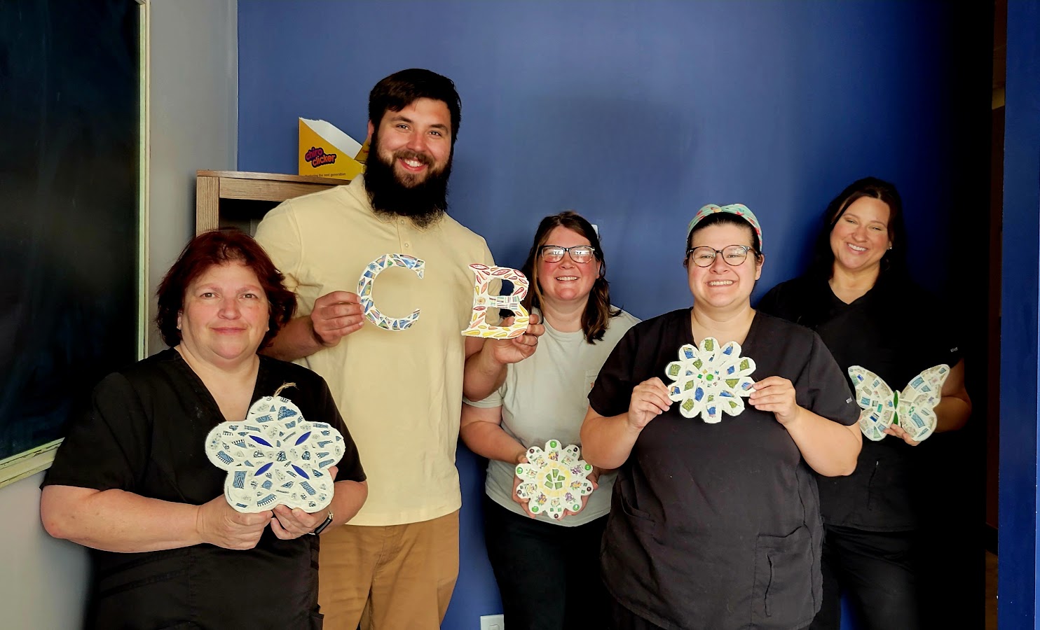 A private mosaic workshop group holding their finished pieces at New Wave Greenwood